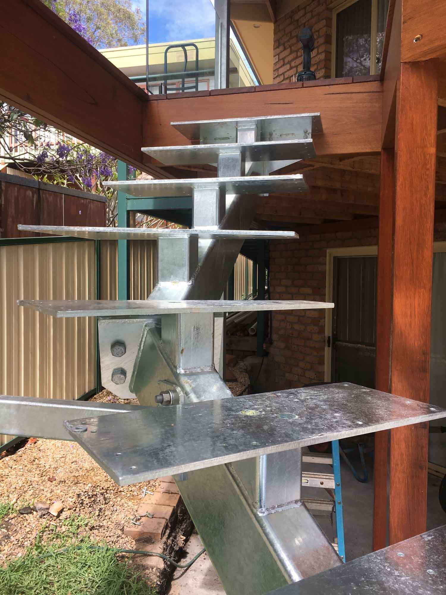 A Metal Staircase Is Being Built On Top Of A Wooden Deck — BM Steel Fabrication In Forster, NSW