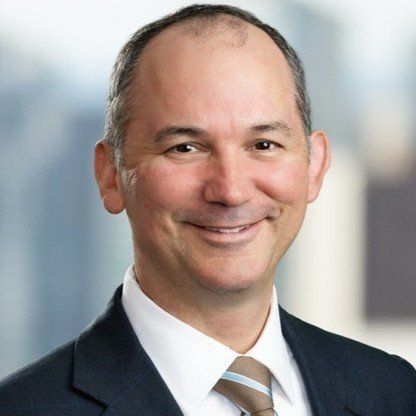 A man in a suit and tie is smiling for the camera