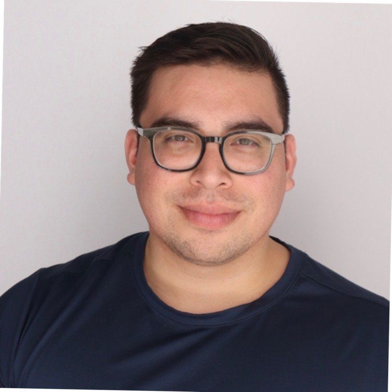 A man wearing glasses and a blue shirt smiles for the camera