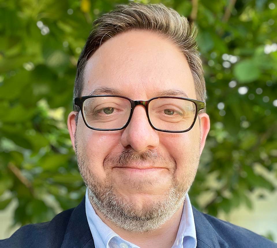 A man with glasses and a beard is smiling for the camera.