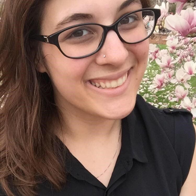 A woman wearing glasses and a nose ring is smiling