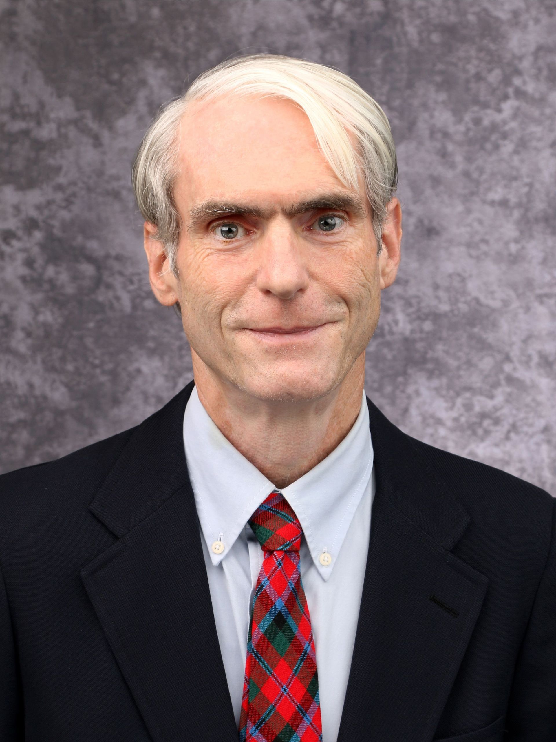 A man in a suit and tie is smiling for the camera