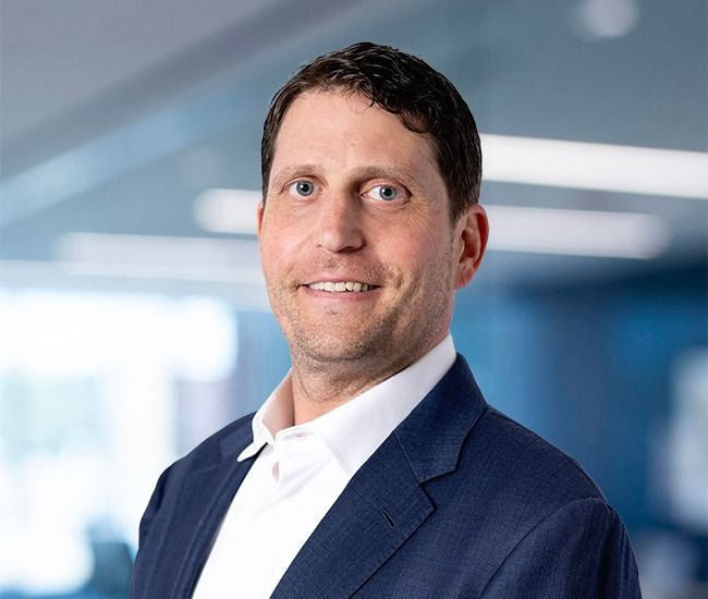 A man in a suit and white shirt is smiling for the camera.