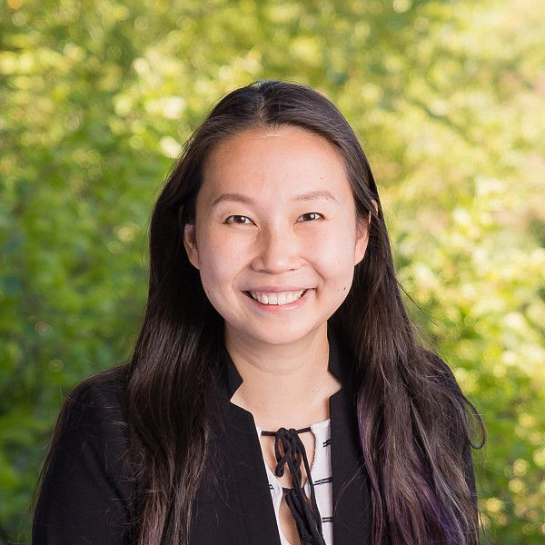 A woman in a black jacket and white shirt is smiling for the camera.
