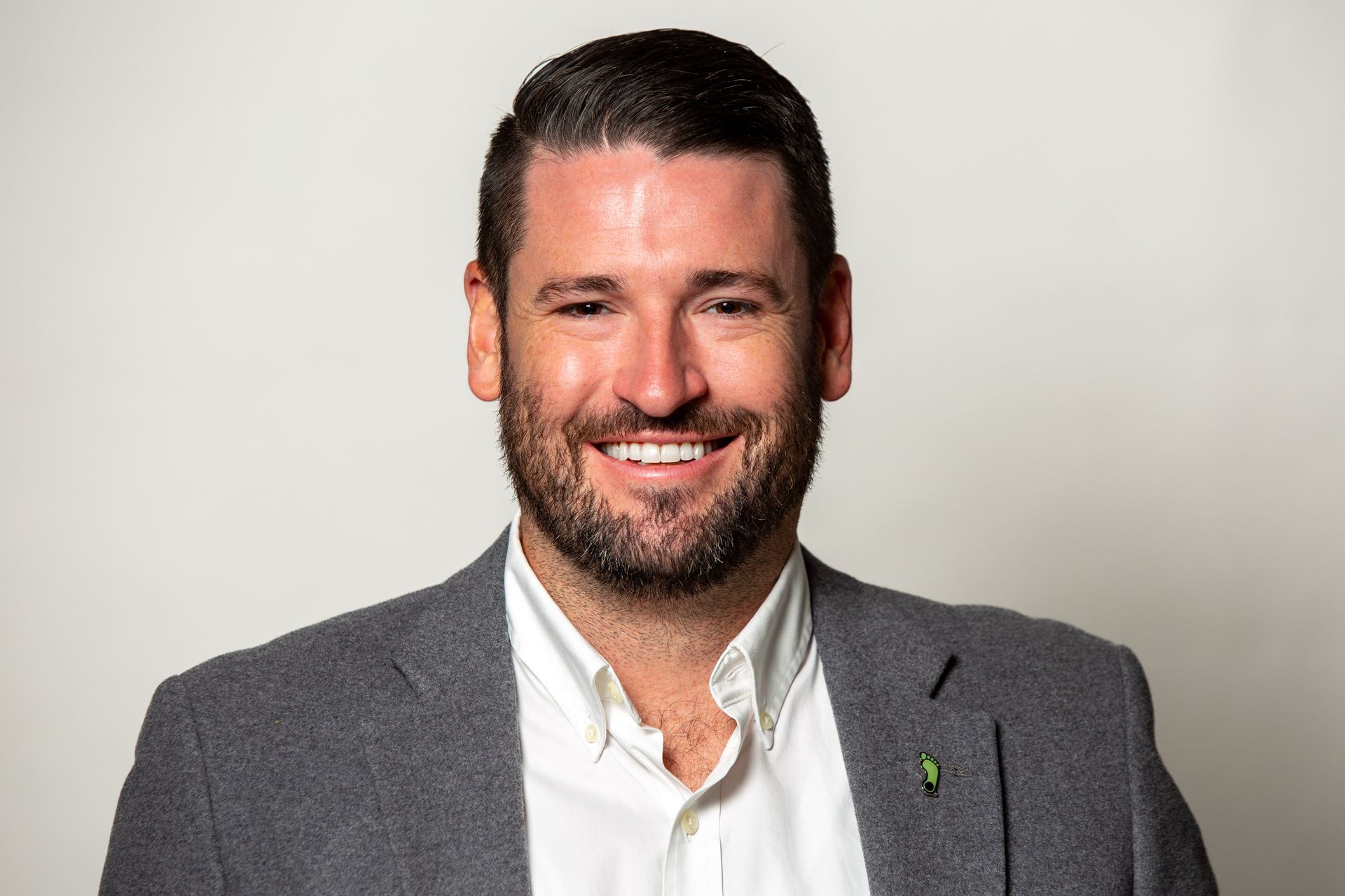 A man with a beard is wearing a suit and smiling for the camera.