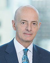 A bald man in a suit and tie is smiling for the camera.