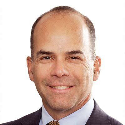 A man in a suit and tie is smiling for the camera.