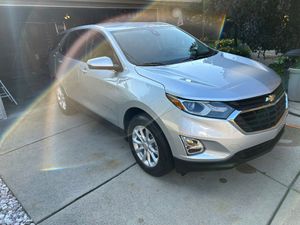 A silver chevrolet equinox is parked in front of a garage.