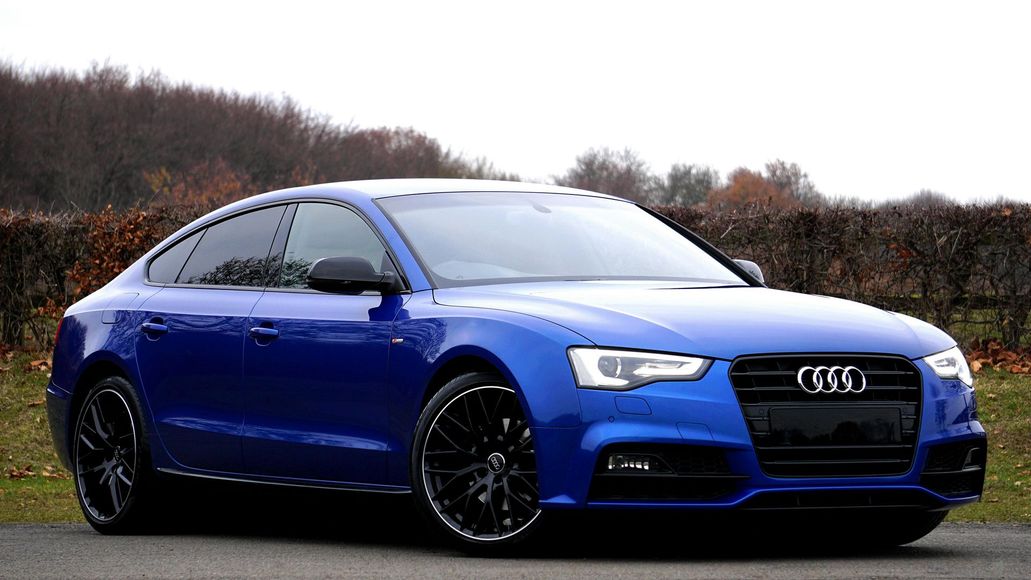 A blue audi a5 is parked on the side of the road.