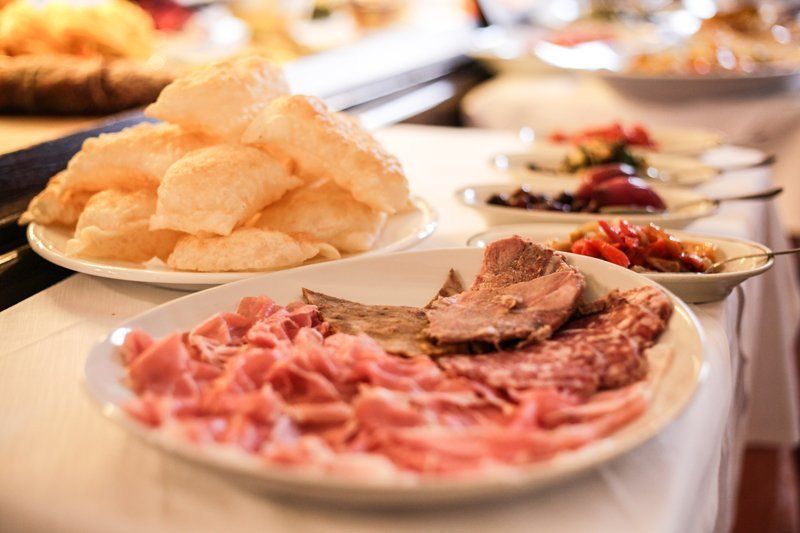 Una ciotola bianca di zuppa con fagioli è appoggiata su un piattino accanto al menu.