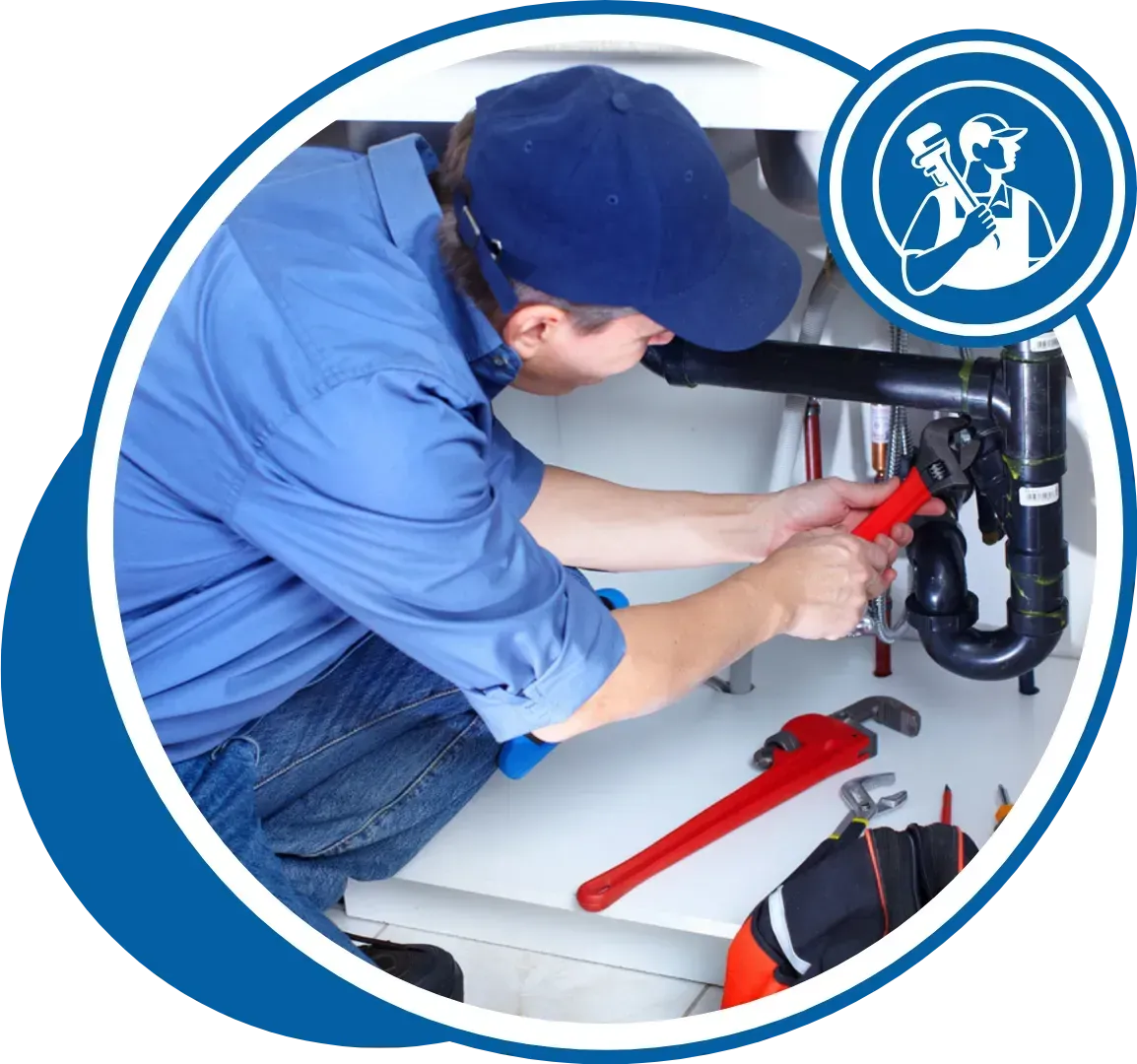 Plumber in blue shirt and cap working under a sink with tools.