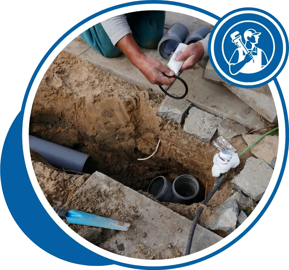 Plumber working on buried pipes, holding an O-ring, in a trench outdoors.