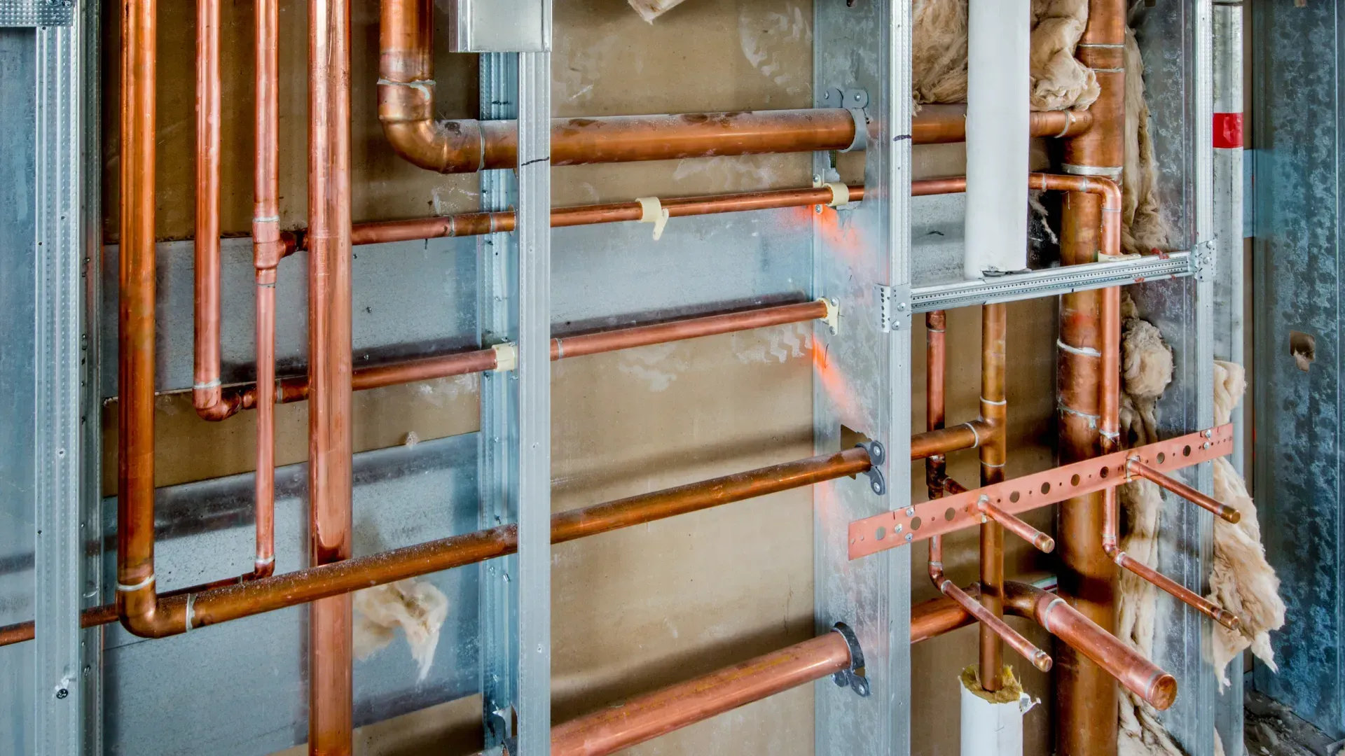 Copper pipes and metal framing inside a wall, under construction.