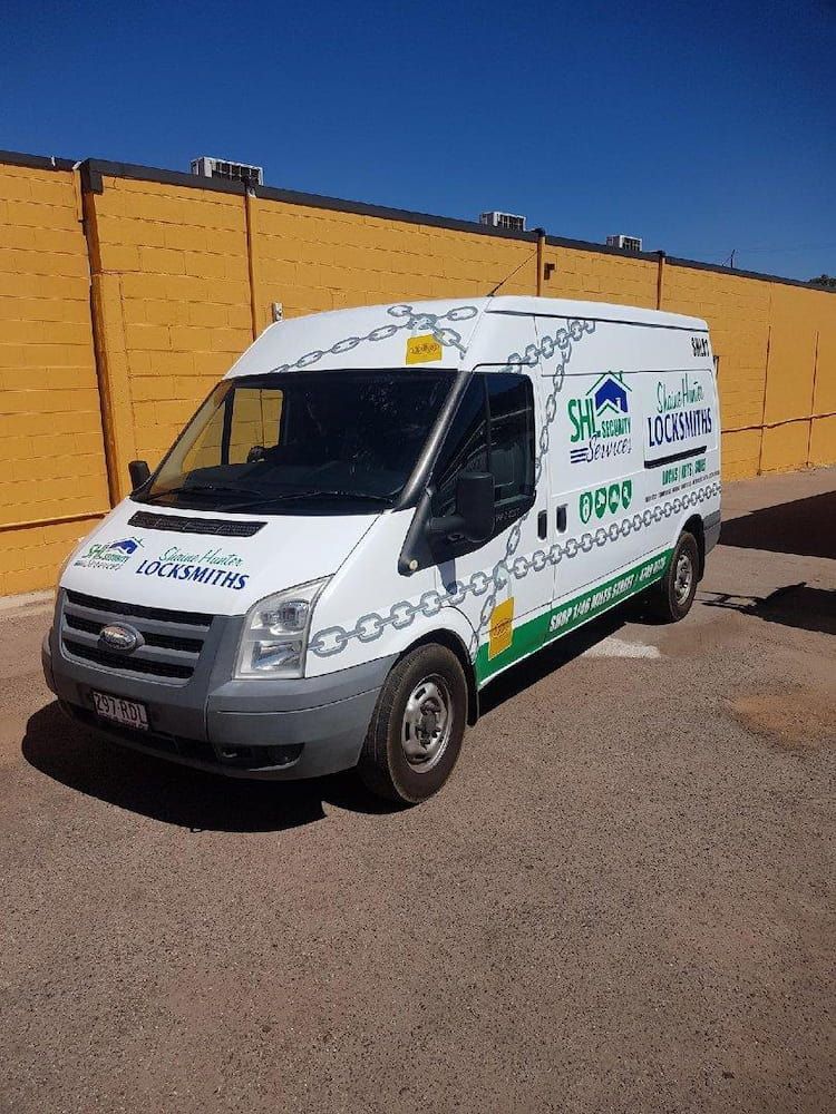 A White Van is Parked in Front of a Yellow Building — Shaine Hunter Locksmiths in Mount Isa, QLD