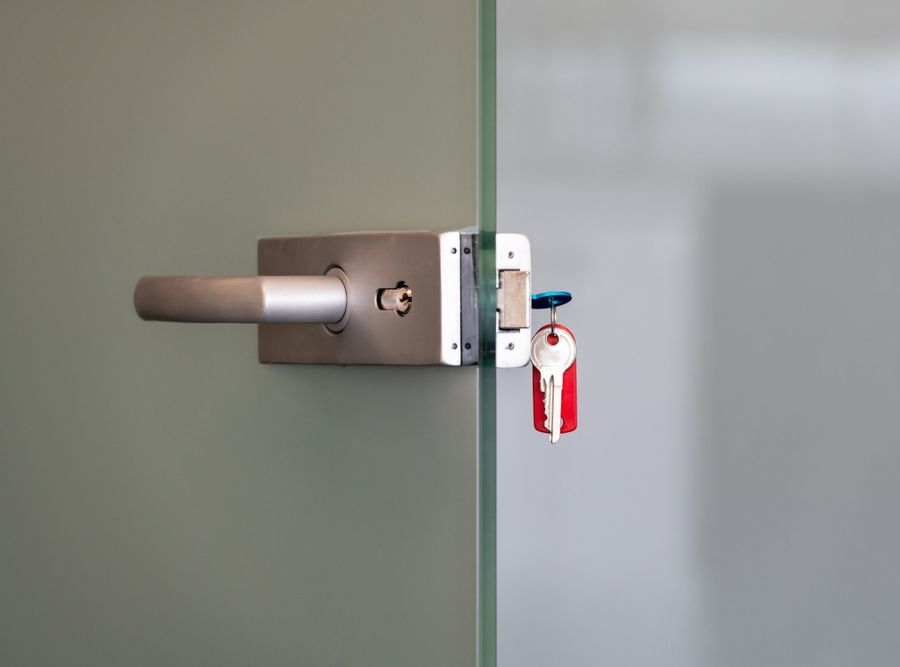 Glass Door With Metal Alloy Handles And Key Chain In Lock — Shaine Hunter Locksmiths in Mount Isa, QLD