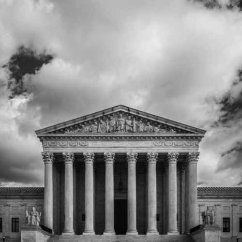 Supreme Court building in black and white with a cloudy sky.