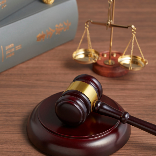 Gavel, scales of justice, and law books on a wooden desk, representing legal proceedings.