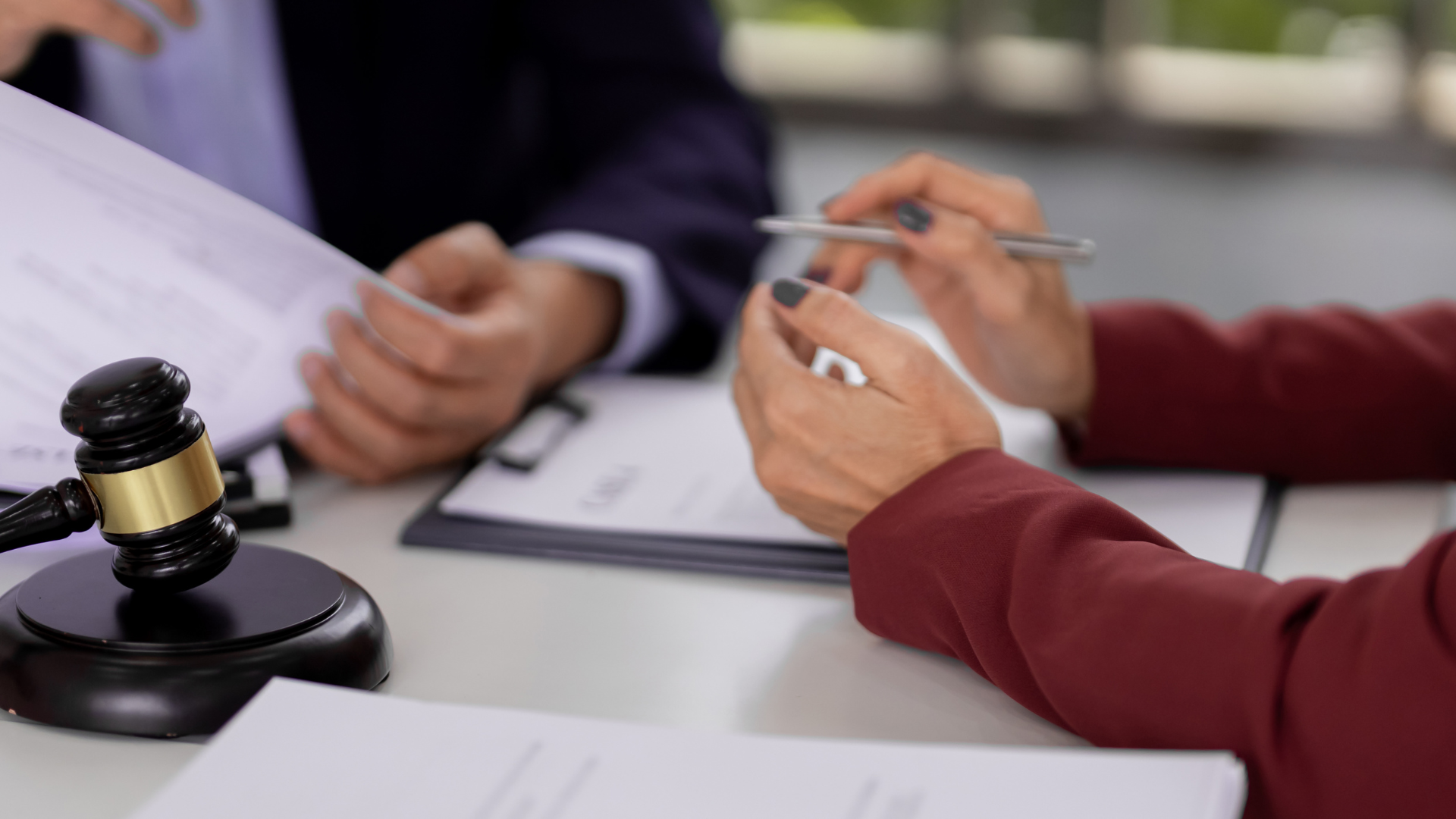 A lawyer and client reviewing documents with a gavel on a desk.