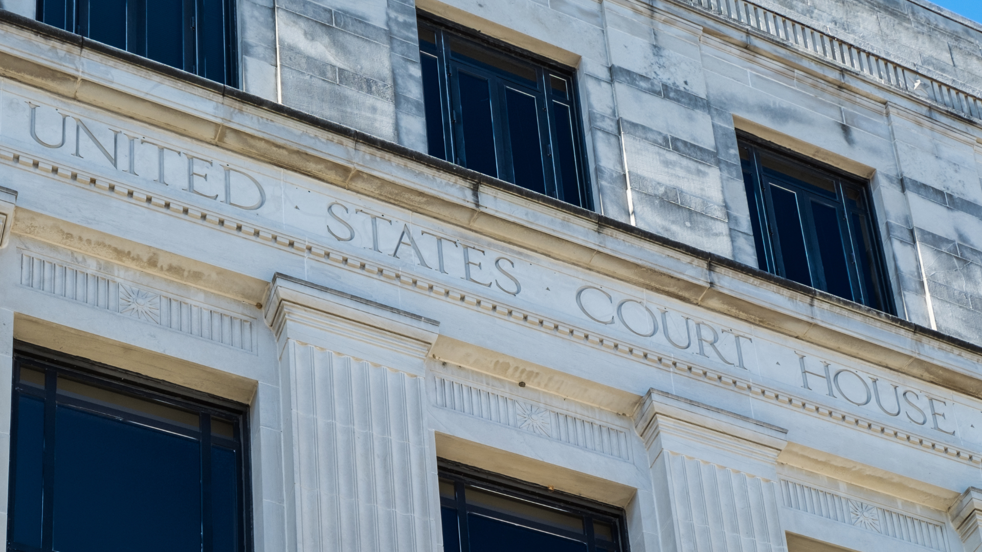Exterior of a United States Court House building with engraved text and dark windows.