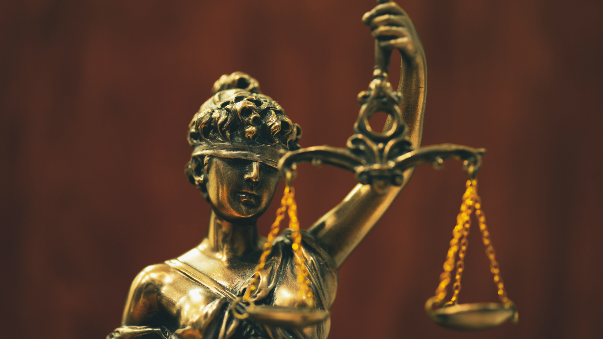 Statue of Lady Justice, blindfolded, holding scales in one hand, golden.