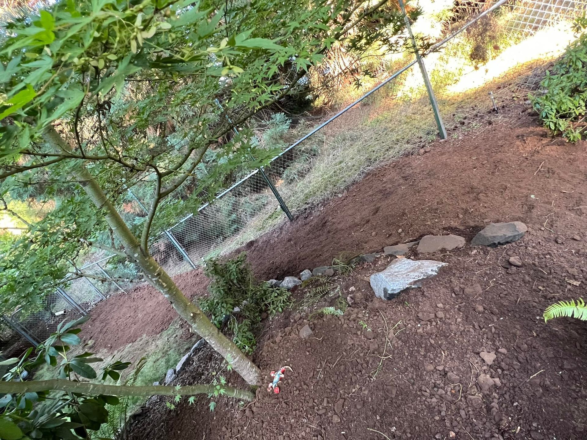 A pile of dirt is sitting next to a chain link fence.