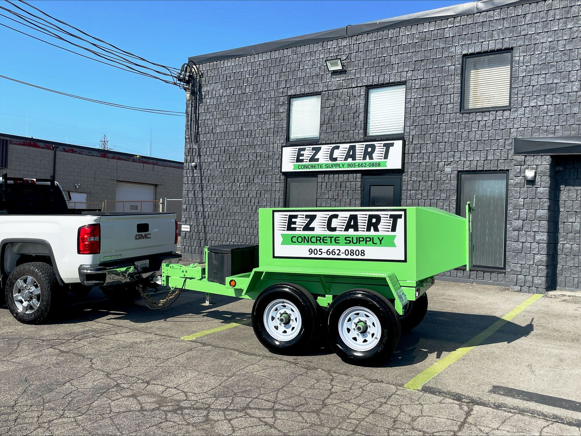 A green trailer is parked in front of a building.
