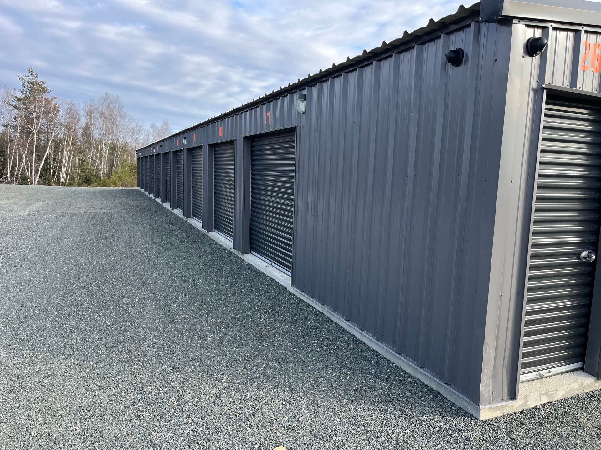 a row of storage units are lined up in a gravel lot with security lights and cameras located in Miramichi, New Brunswick.