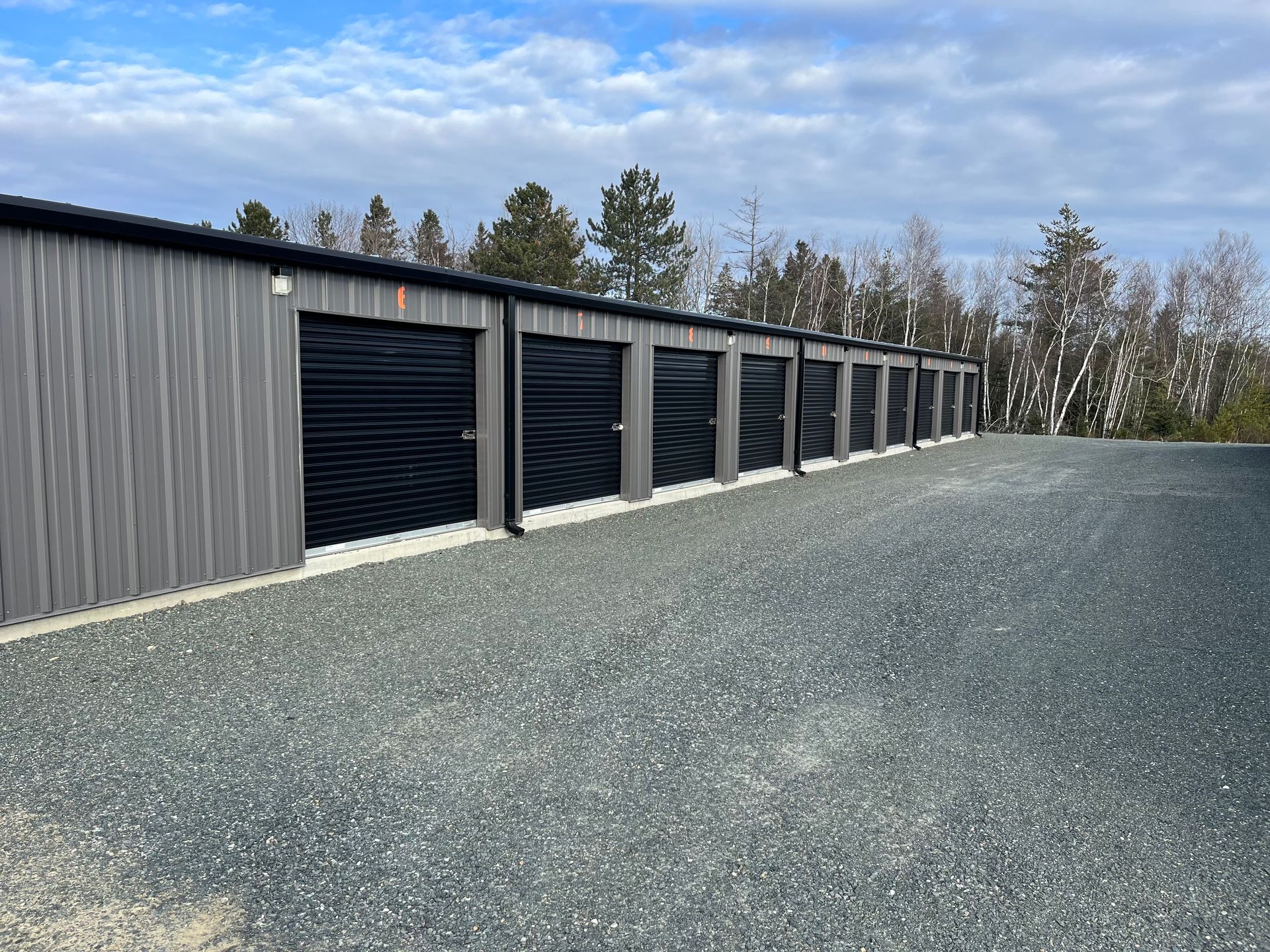 a row of storage units are lined up in a gravel lot located in Miramichi, New Brunswick.