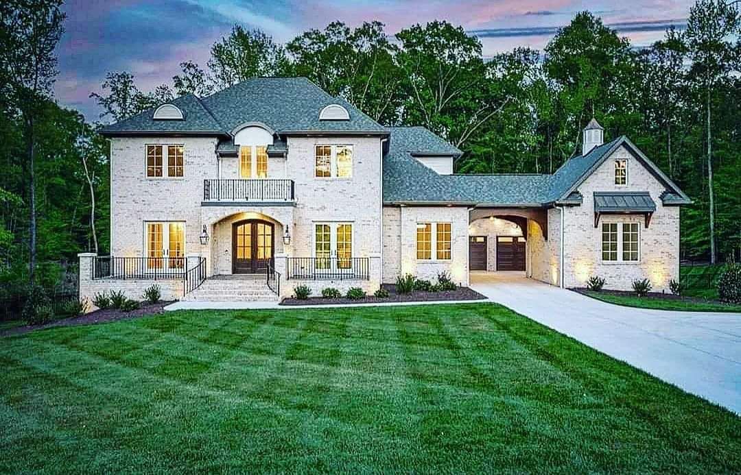 A Large White House With a Gray Roof is Sitting on Top of a Lush Green Lawn