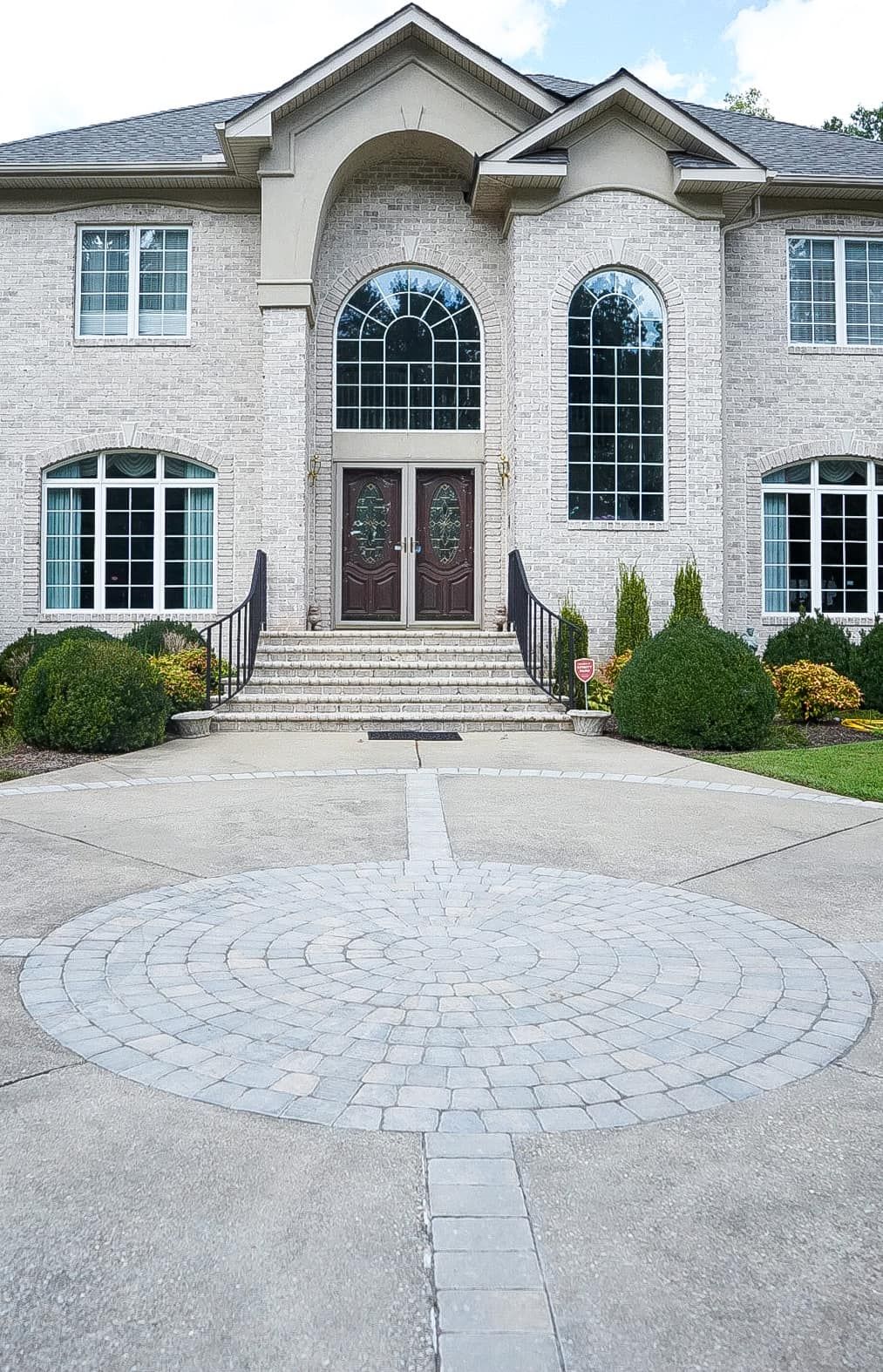 A Large Brick House With a Circular Driveway in Front of It