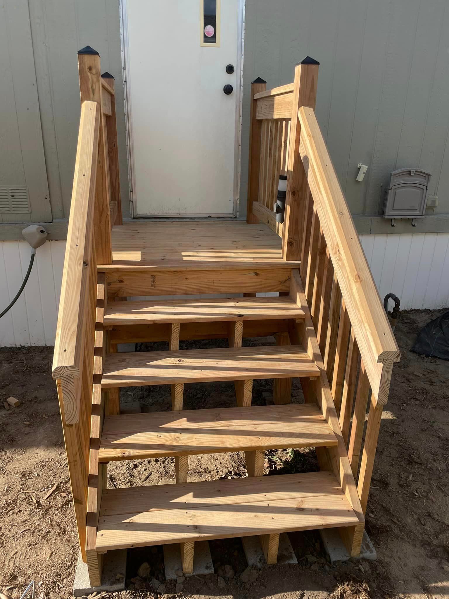 A set of wooden stairs leading up to a white door.