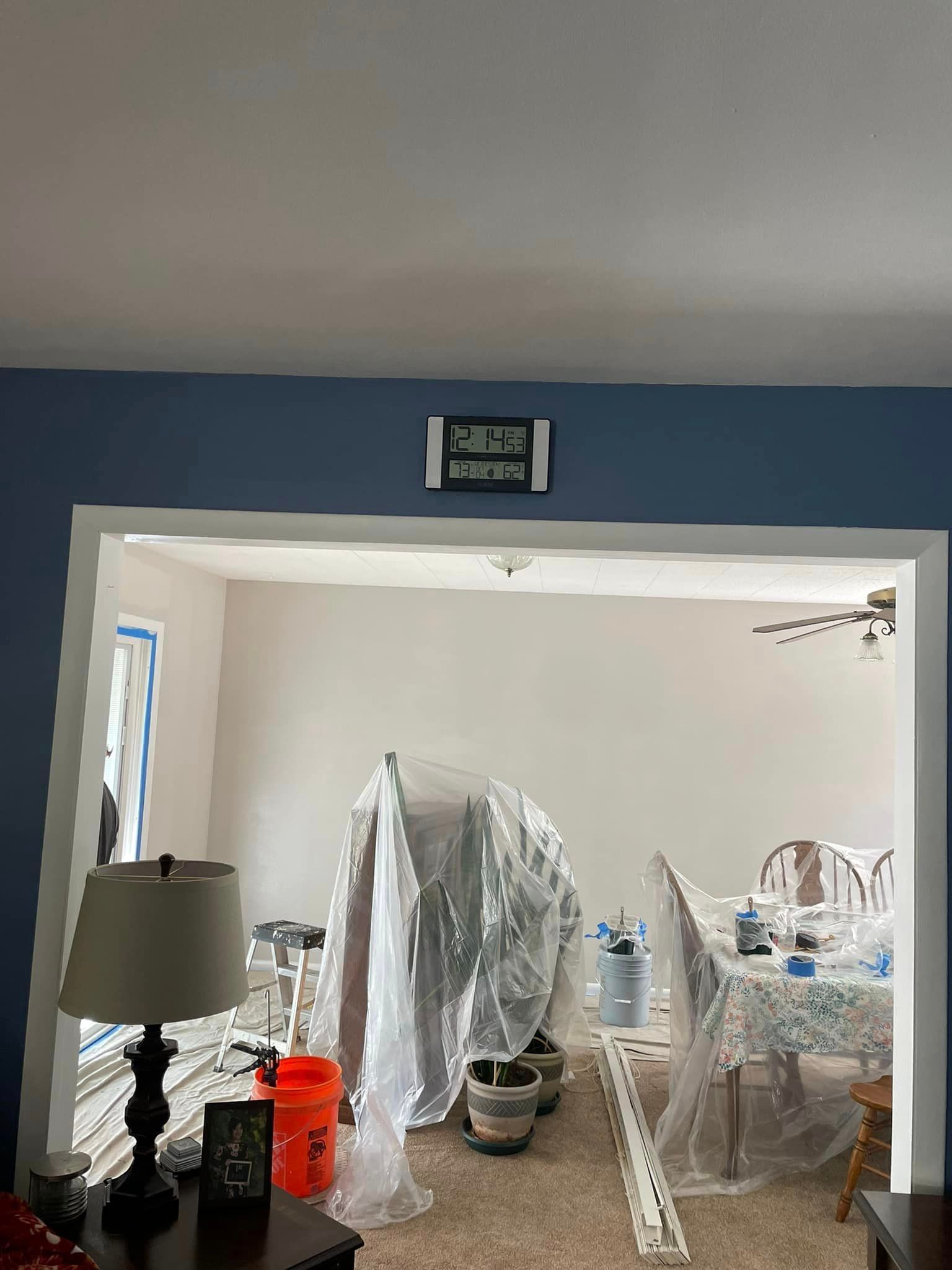 A living room with a table and chairs covered in plastic.