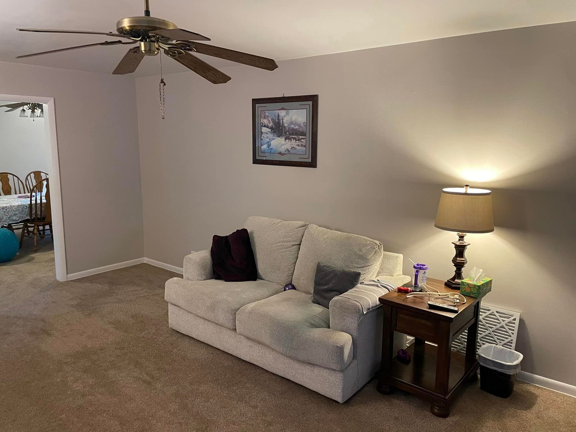 A living room with a couch , table , lamp and ceiling fan.