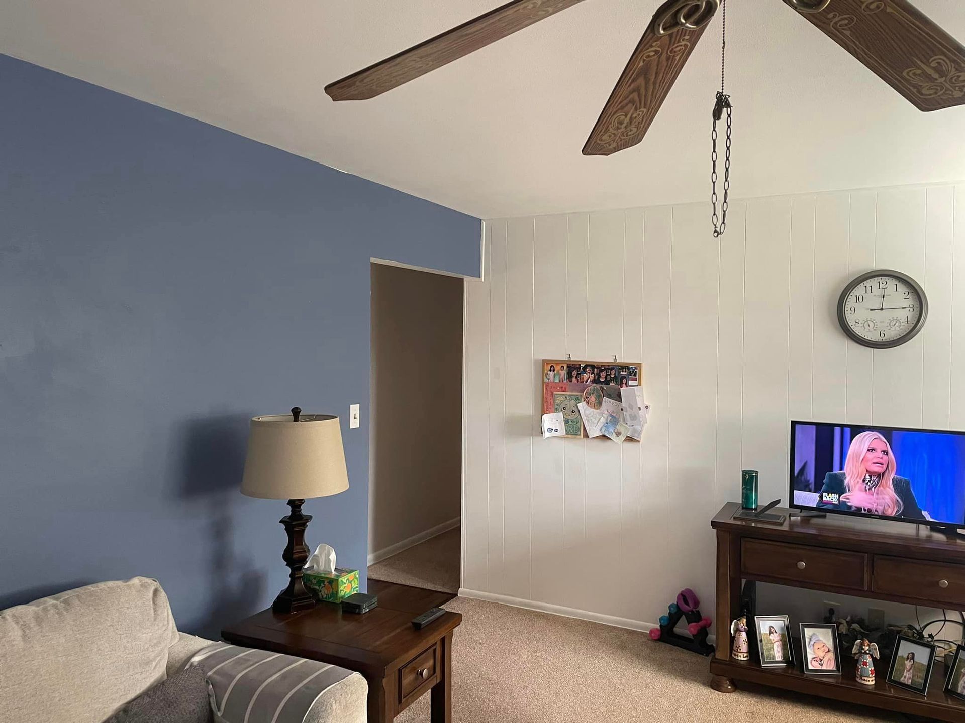 A living room with a couch , table , television and ceiling fan.