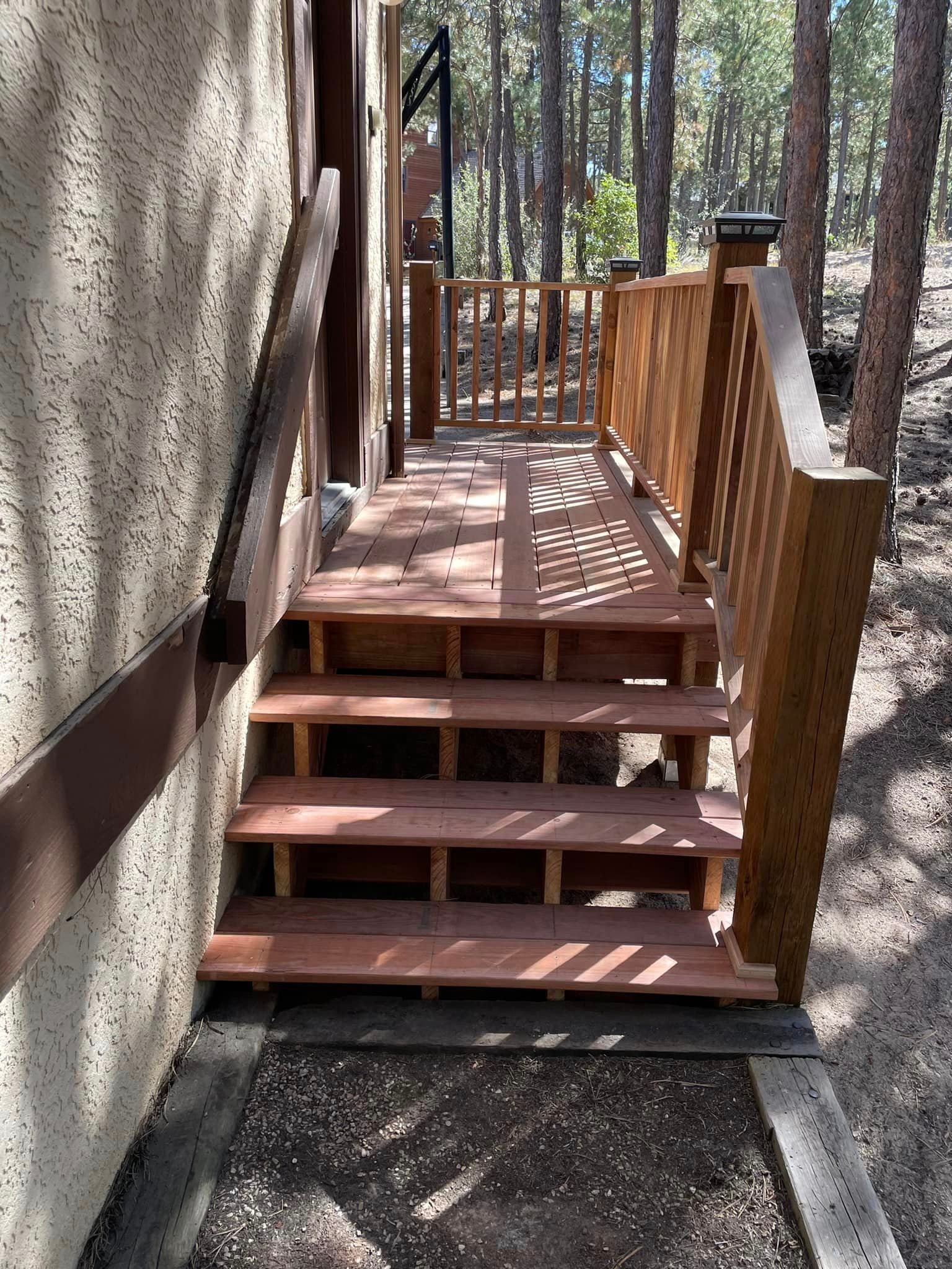 A wooden deck with stairs leading up to it and a railing.