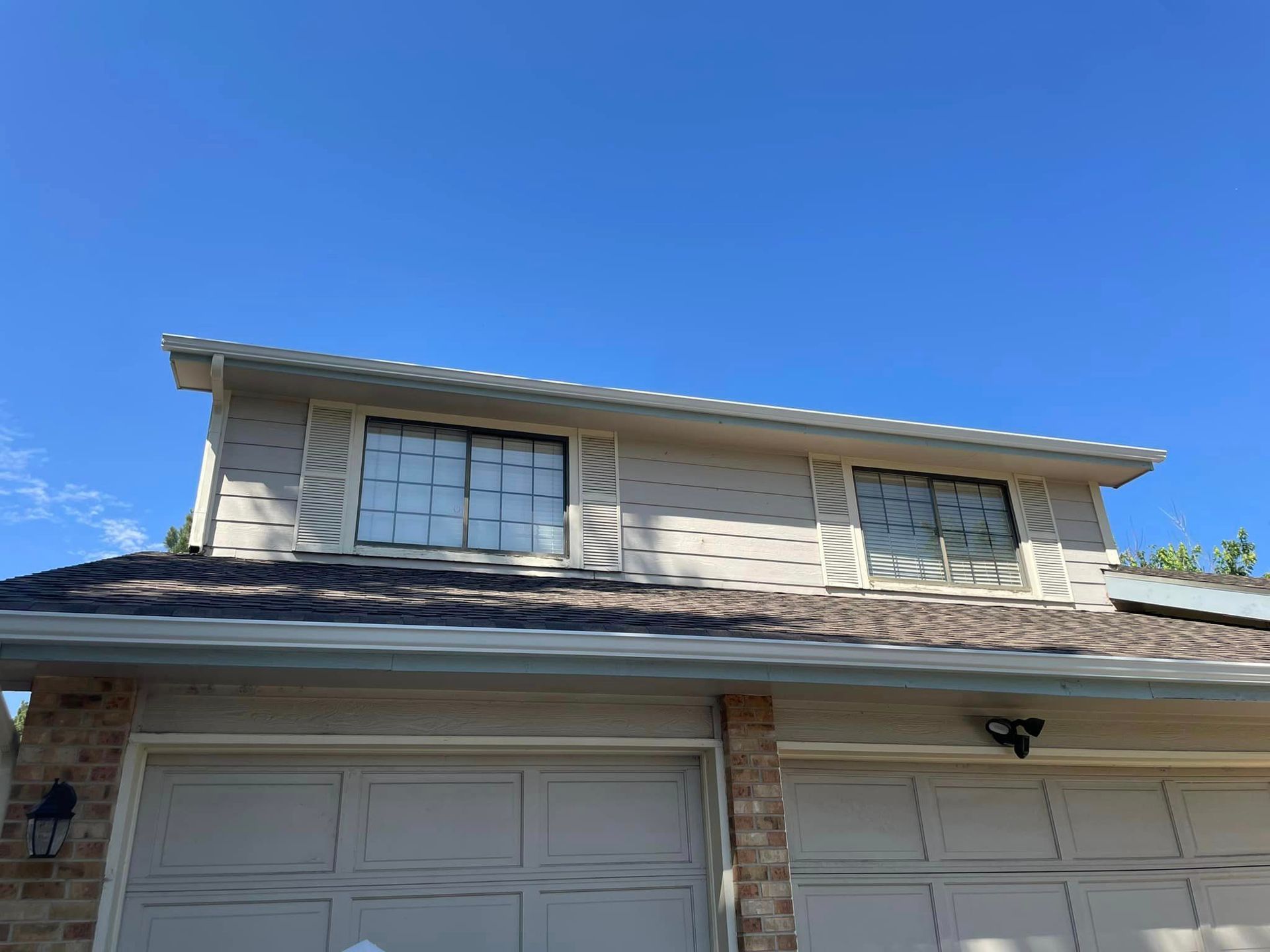 A white house with a garage and a blue sky in the background.
