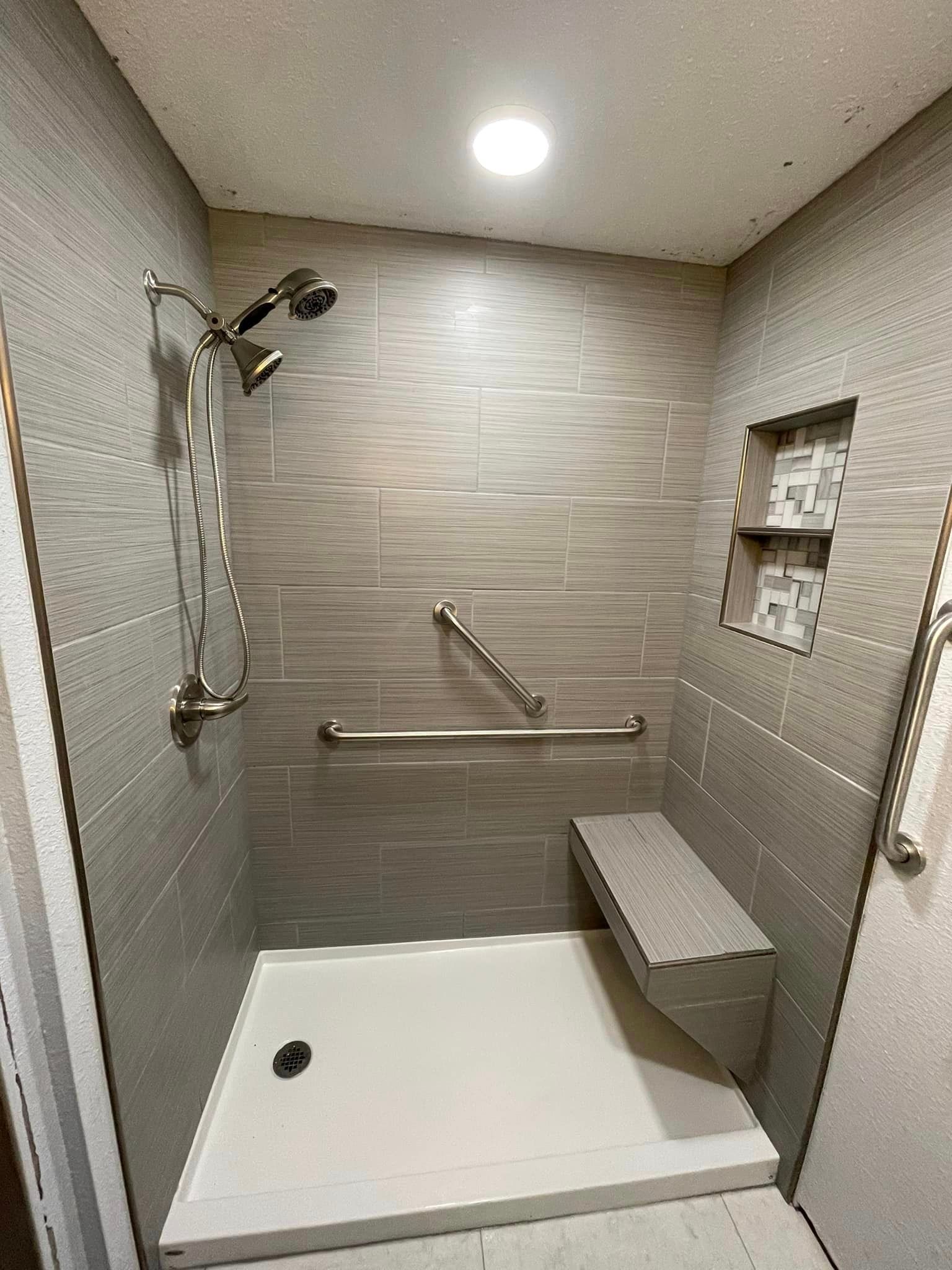 A bathroom with a walk in shower and a bench.