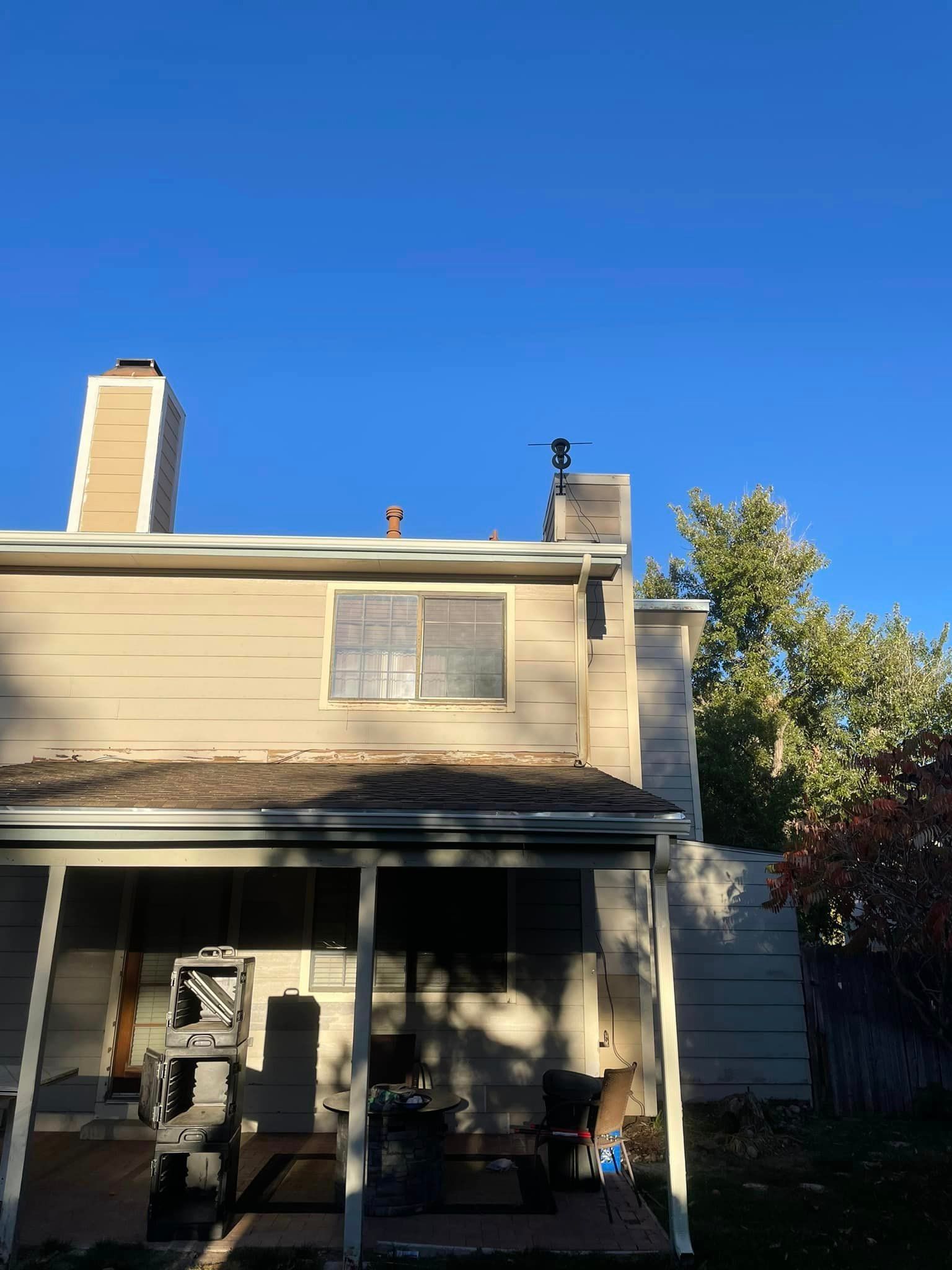 A house with a chimney on the roof and a porch.