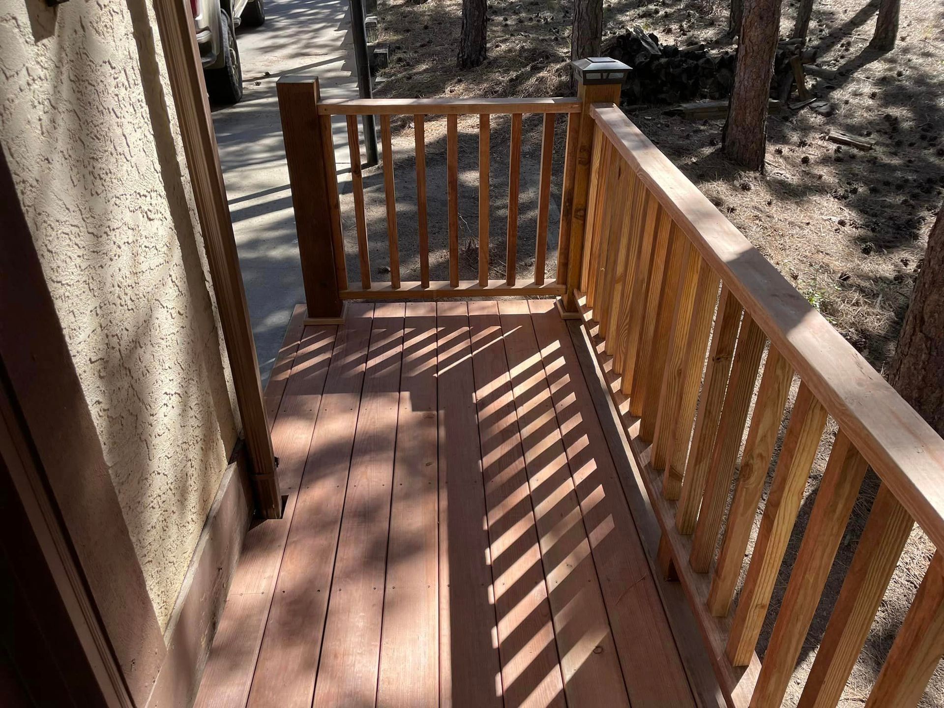 A wooden deck with a wooden railing and trees in the background