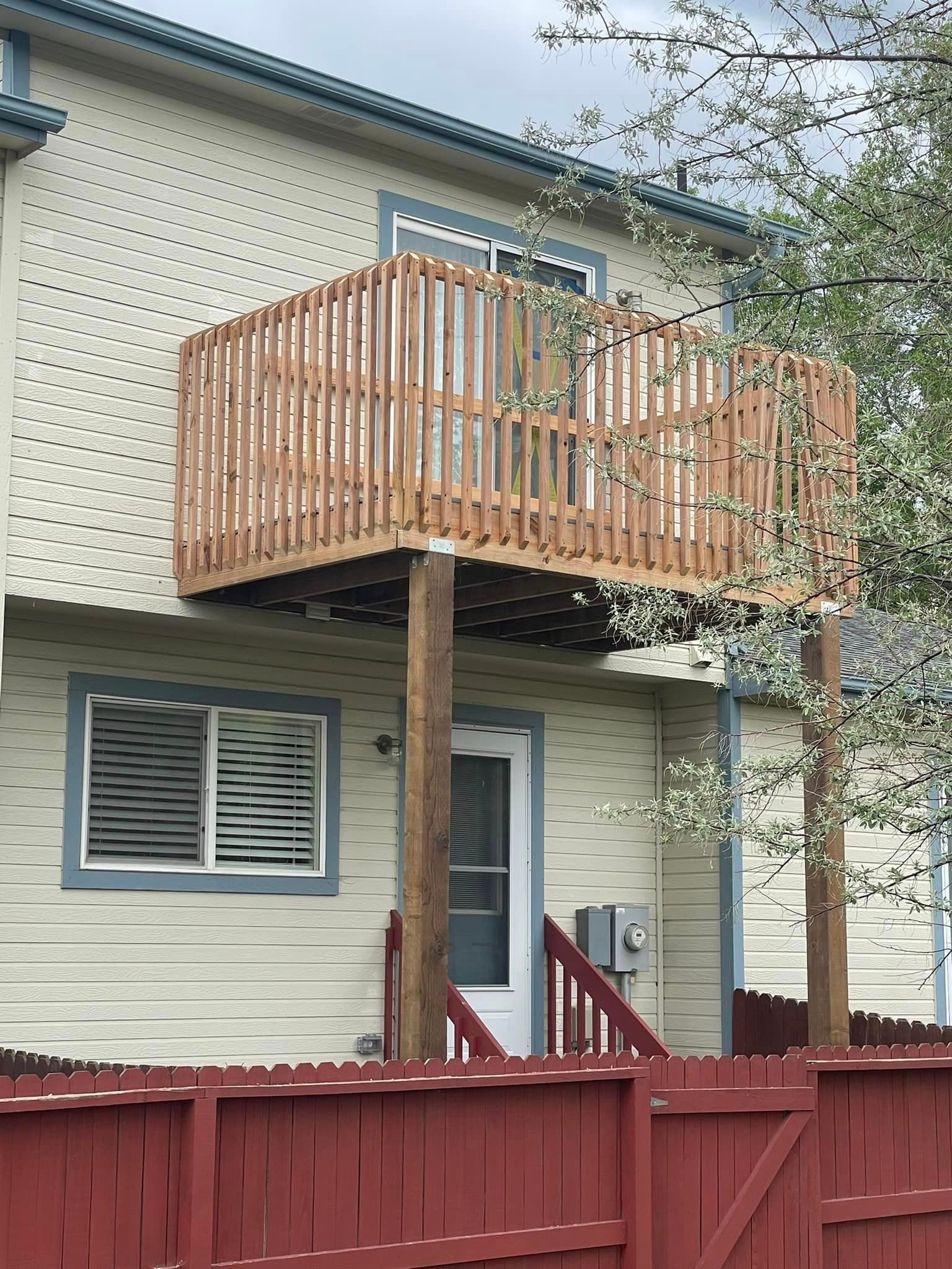 A house with a wooden deck and a red fence
