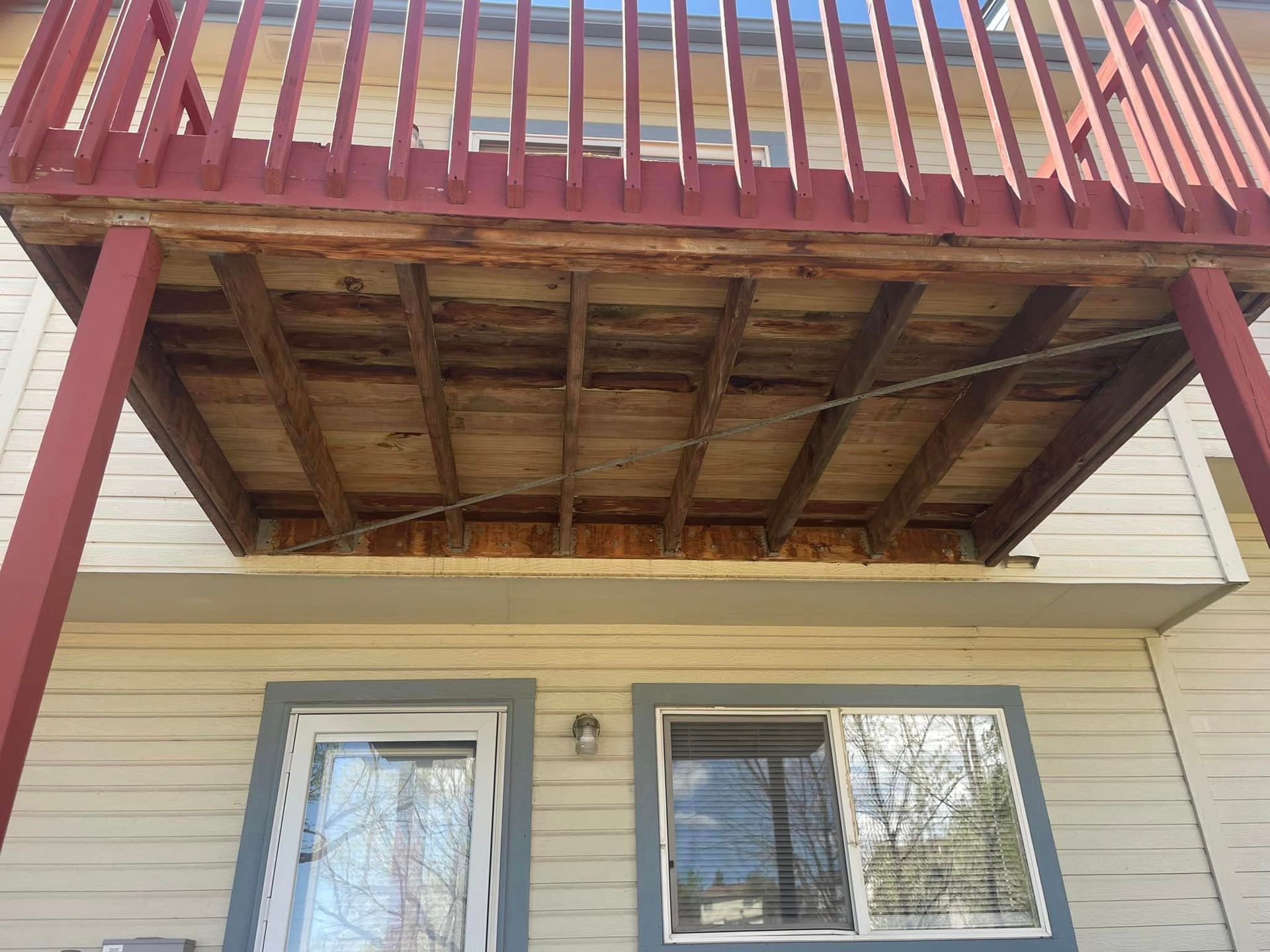 A house with a wooden deck and a red railing.