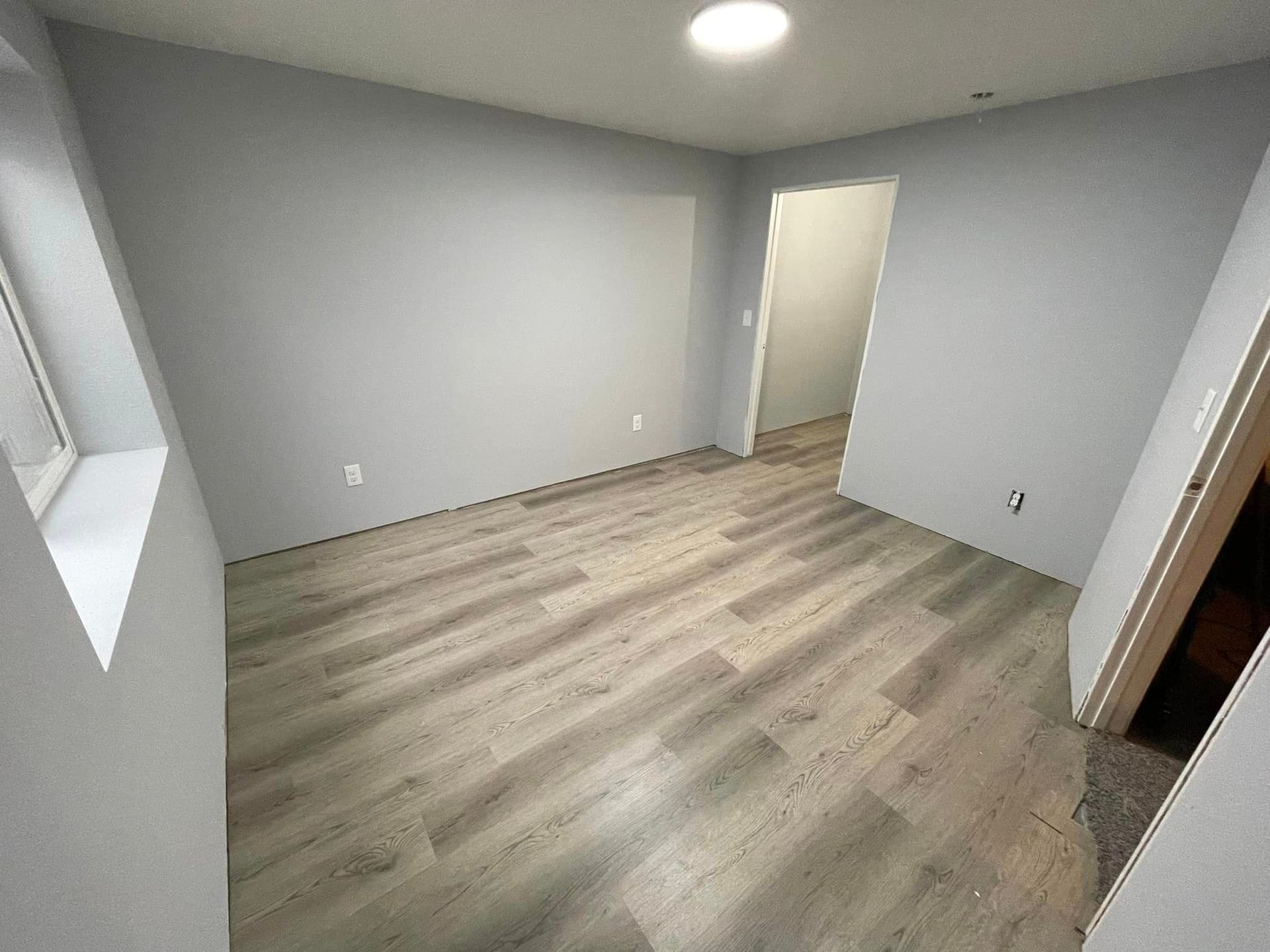 A bedroom with hardwood floors and gray walls.