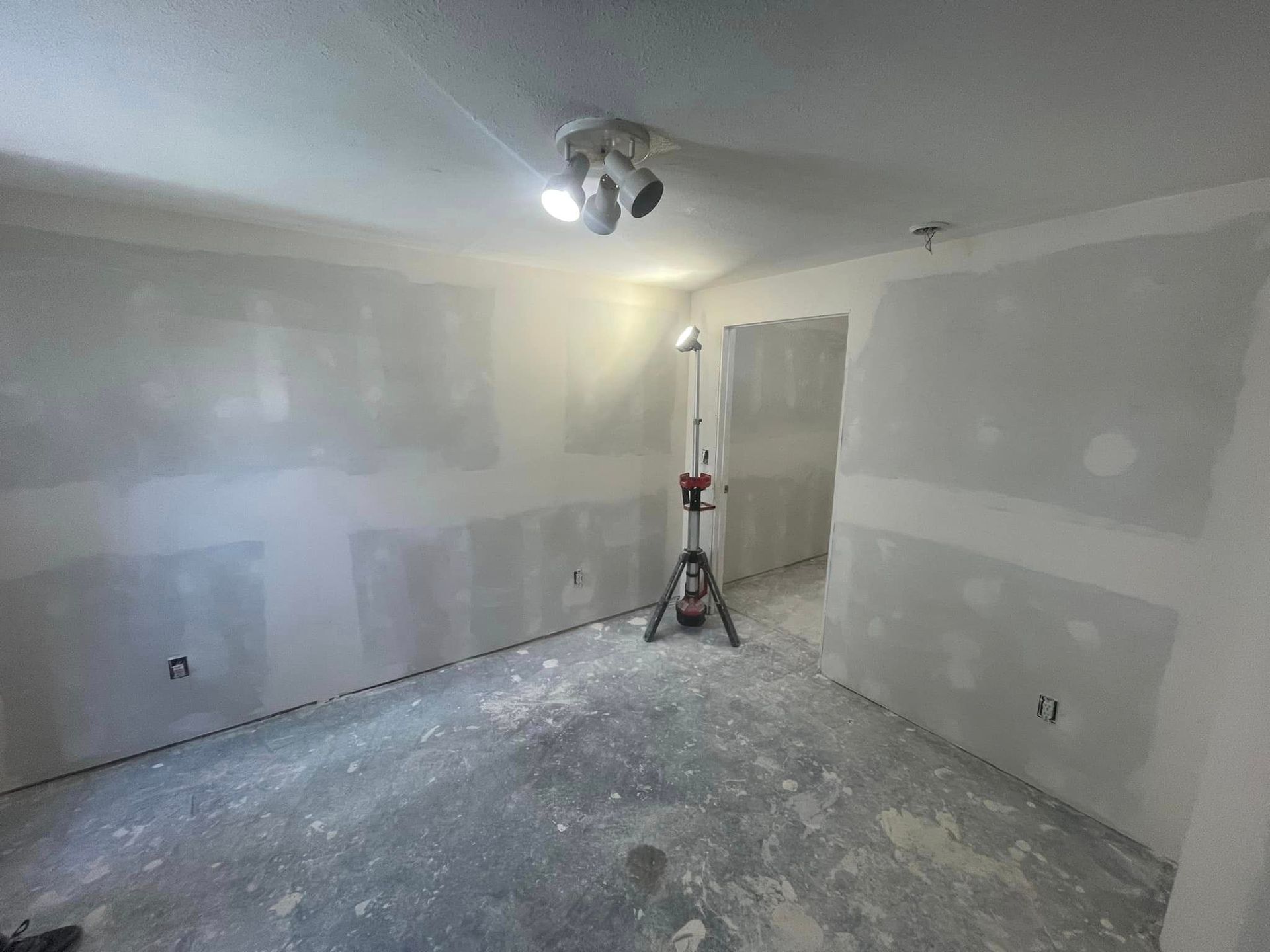A room with drywall walls and a light on the floor.