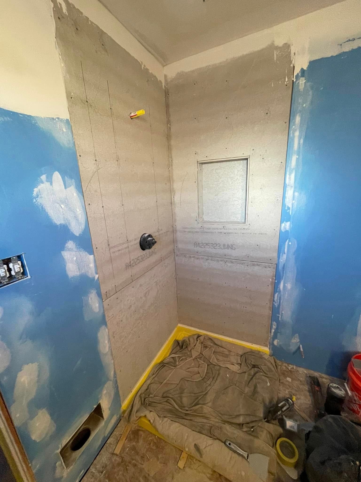 A bathroom under construction with blue walls and a shower.