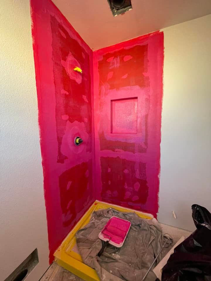 A bathroom is being painted pink with a roller.