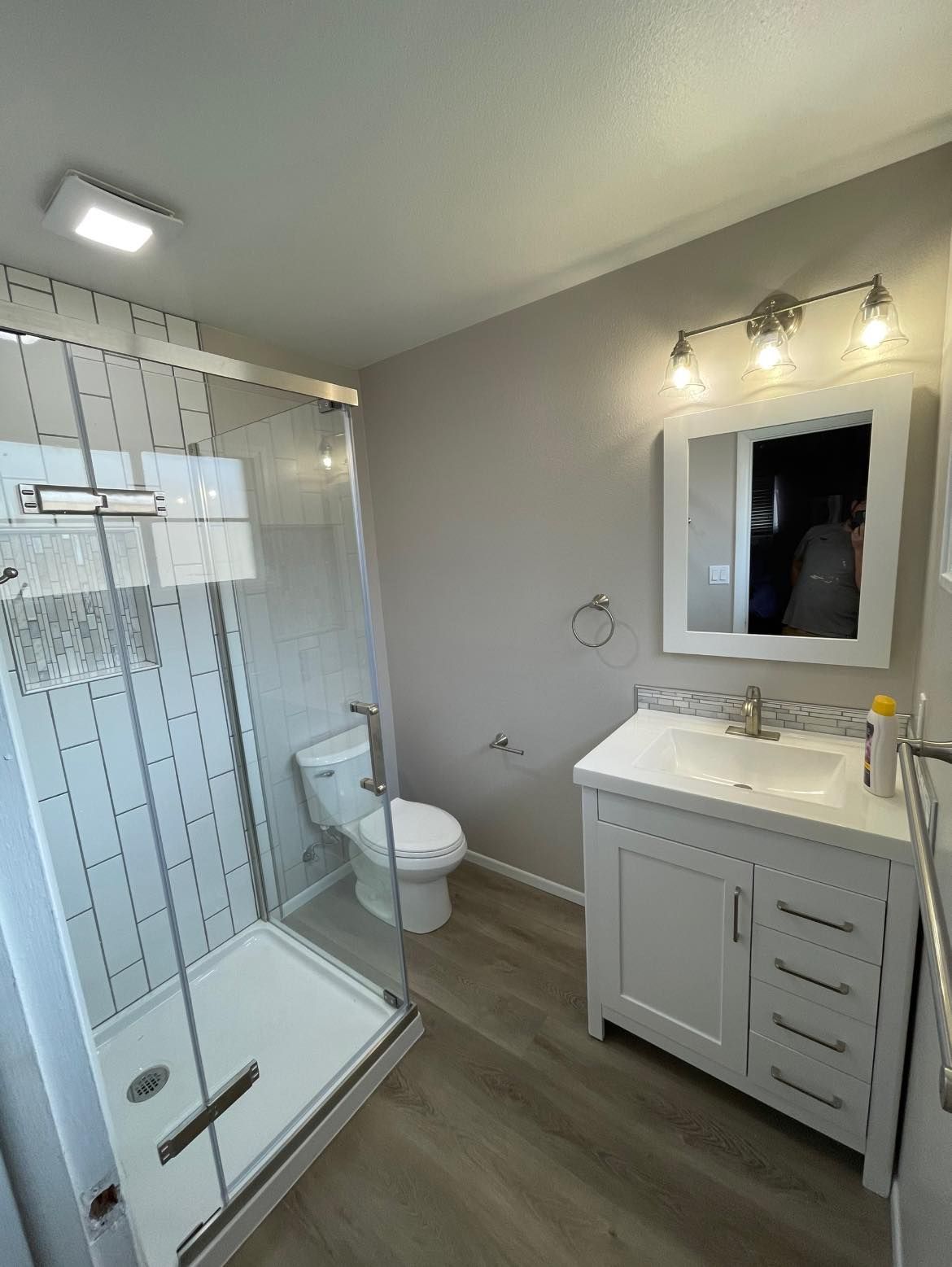 A bathroom with a toilet , sink , shower and mirror.
