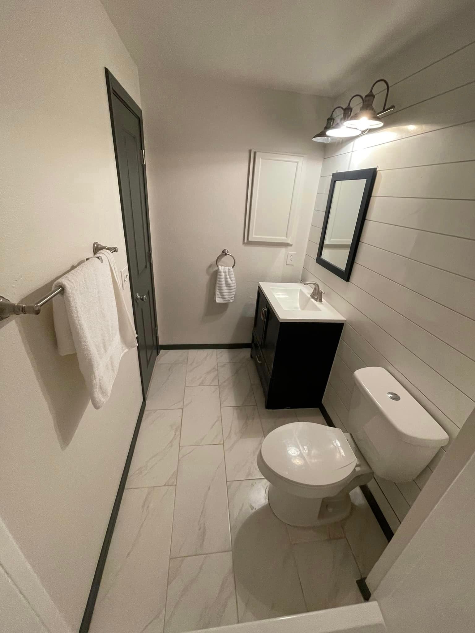 A bathroom with a toilet , sink and mirror.
