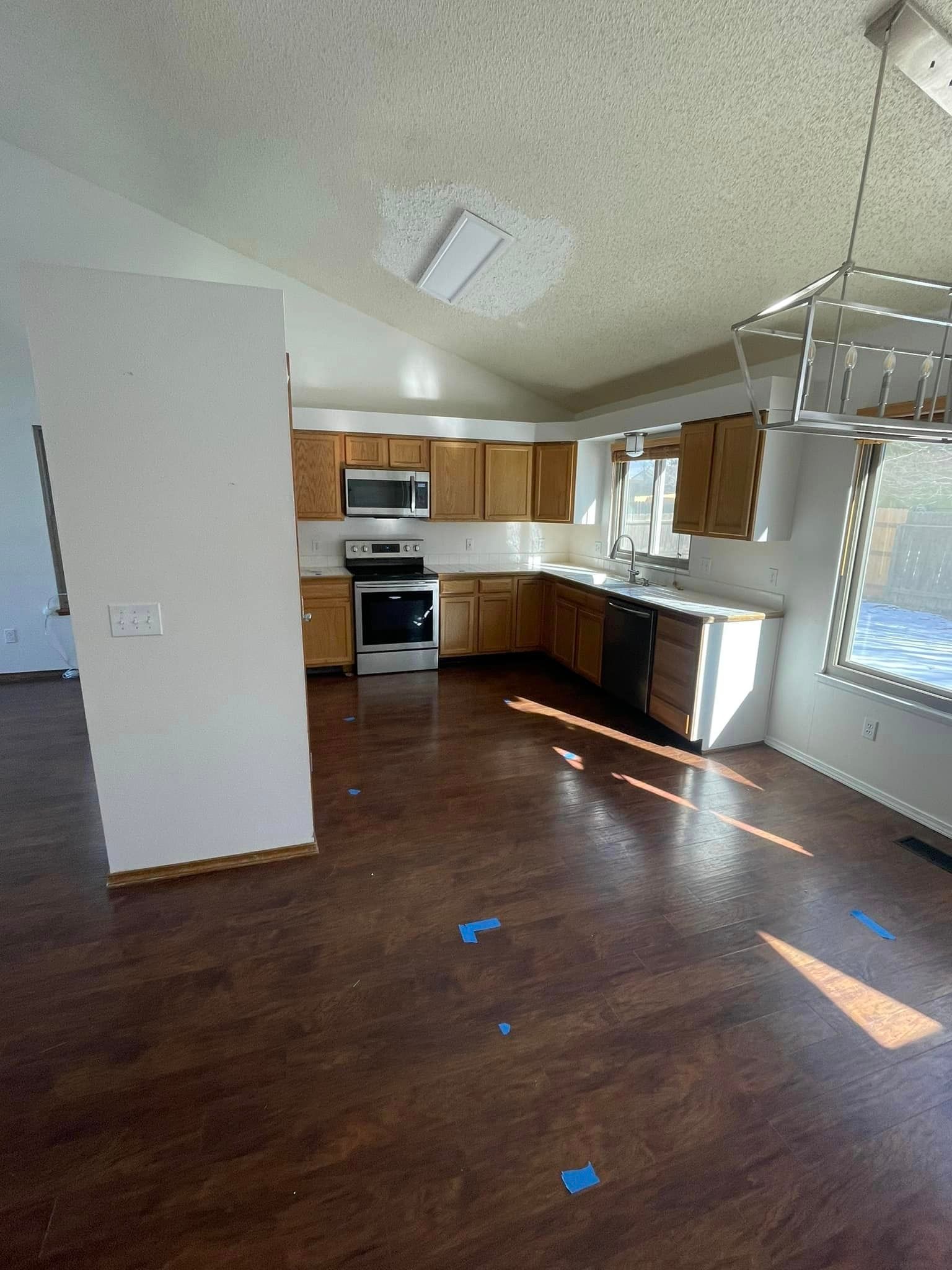 A kitchen with wooden cabinets , a stove , a microwave , and a sink.