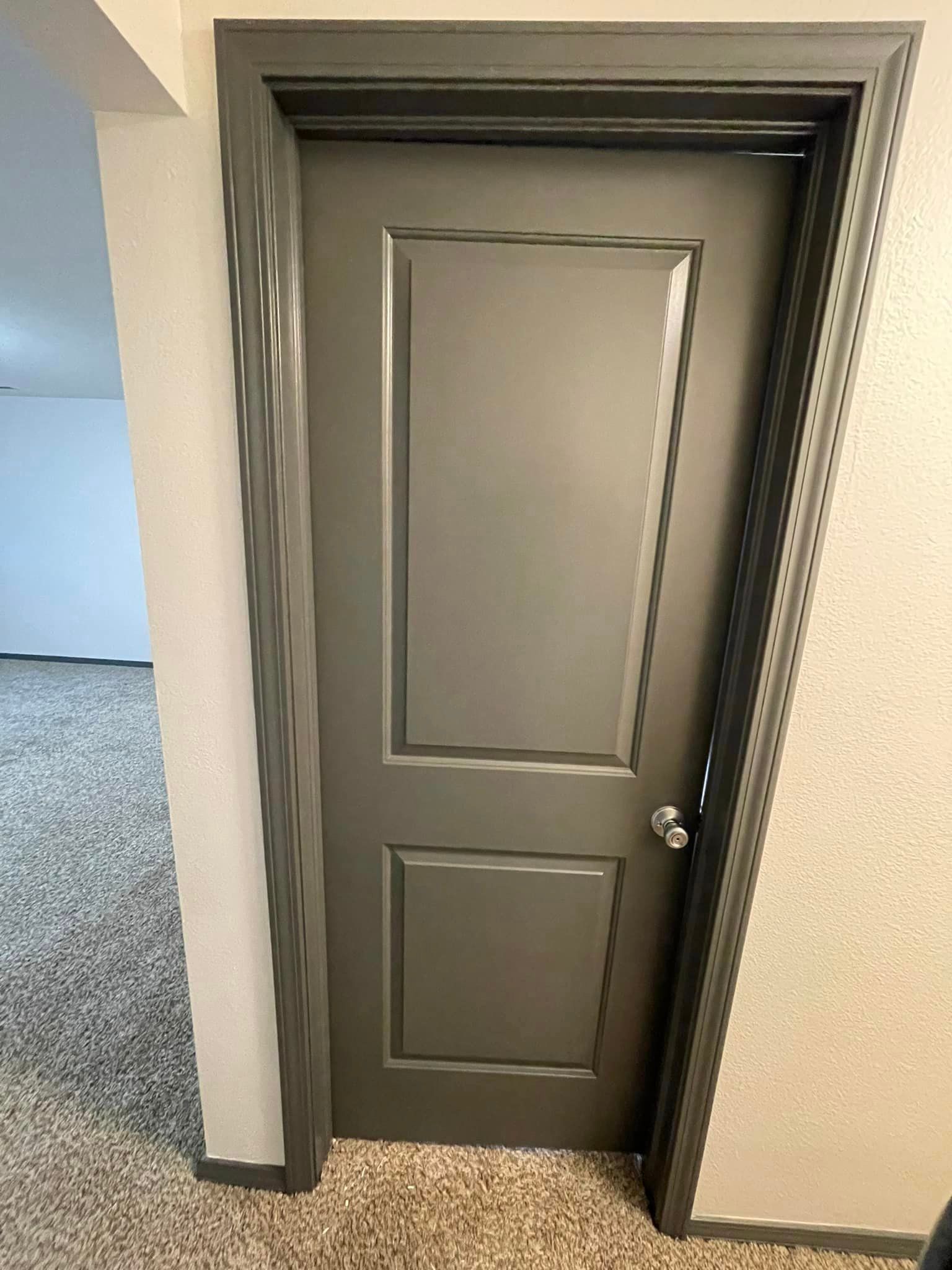 A gray door is sitting in a hallway next to a wall.
