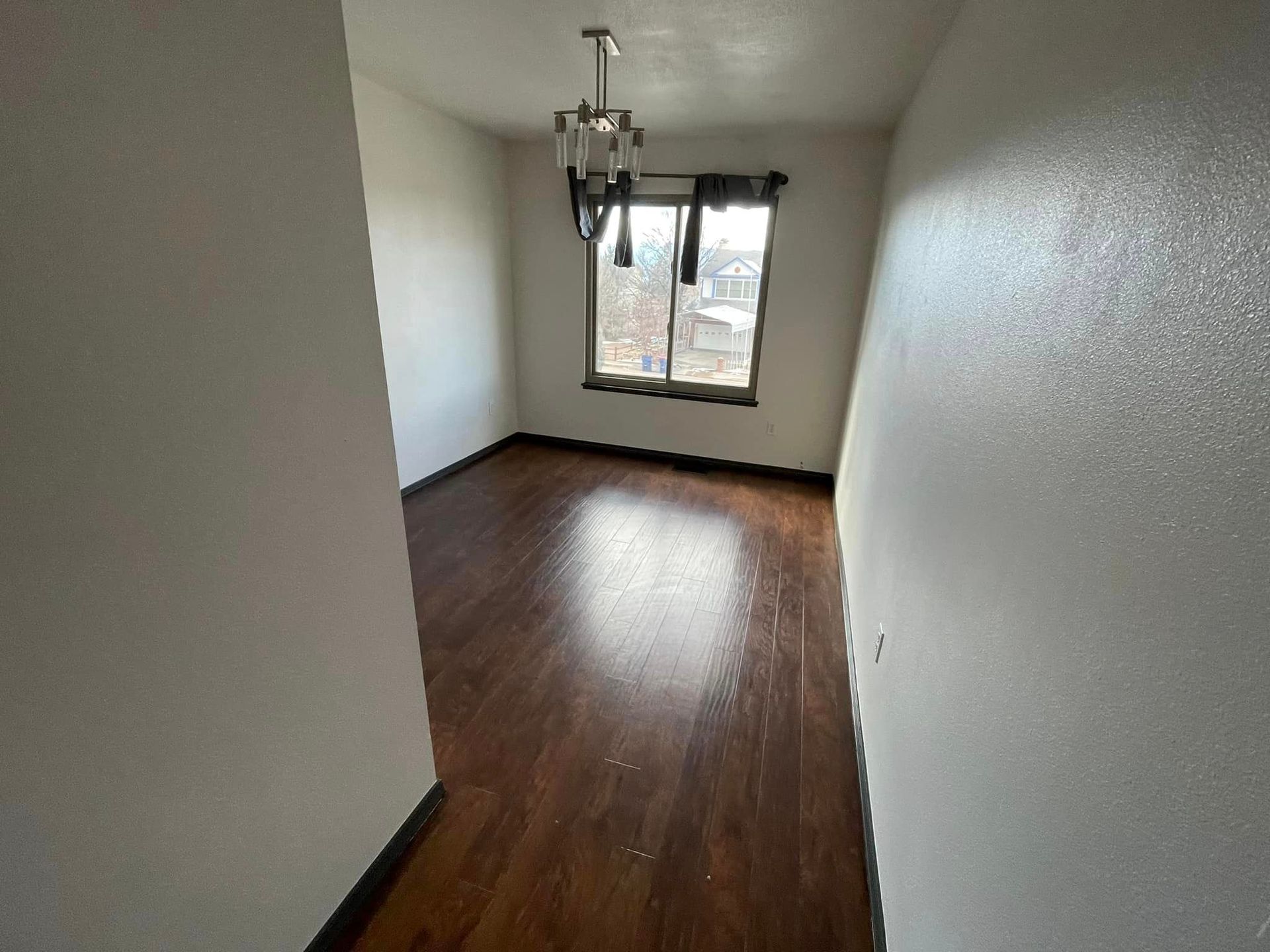 An empty room with hardwood floors and a window.